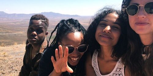 Filmstill aus High Fantasy - vier junge Erwachsene blicken fröhlich und neutral in Kamera, im Hintergund Wüste